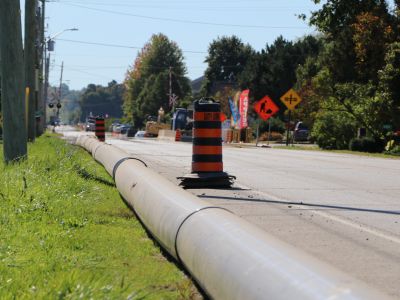 Watermain pipe on the side of a road with pylons.